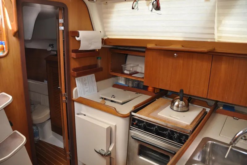 Slide: The Image of 2003 Catalina 387 yacht interior with compact kitchen, stove, and wooden cabinetry. - 50