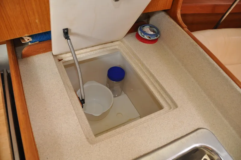 Slide: The Image of Storage compartment in a 2003 Catalina 387 yacht kitchen with containers and a faucet. - 57