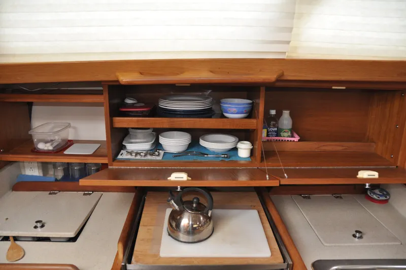 Slide: The Image of Compact kitchen in a 2003 Catalina 387 sailboat with wooden cabinets and a kettle. - 58