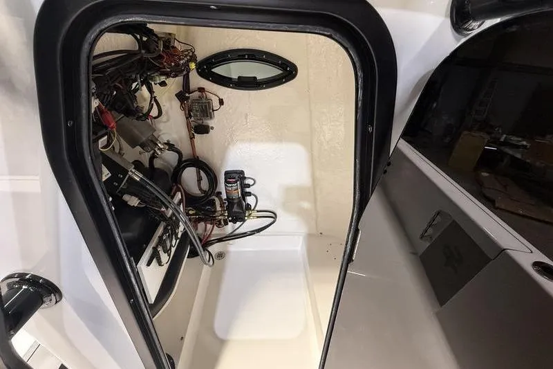 Slide: The Image of Interior view of 2026 Sea Pro 230 Bay boat's storage compartment with wiring and equipment. - 12