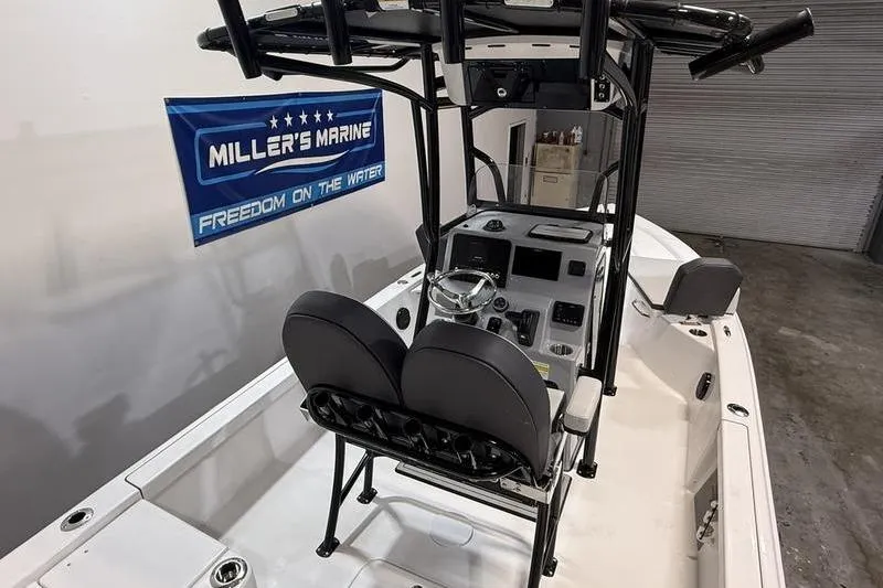 Slide: The Image of 2026 Sea Pro 230 Bay boat interior with helm, seats, and Miller's Marine banner. - 16