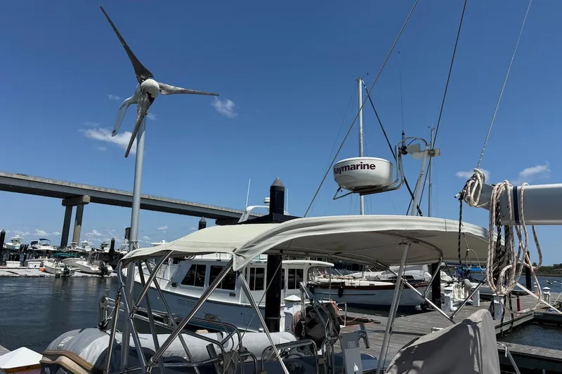Slide: The Image of Catalina 380 sailboat docked, featuring wind turbine and Raymarine equipment, under clear blue sky. - 20