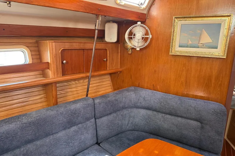 Slide: The Image of Interior of a 1998 Catalina 380 sailboat with wood paneling and blue seating. - 26