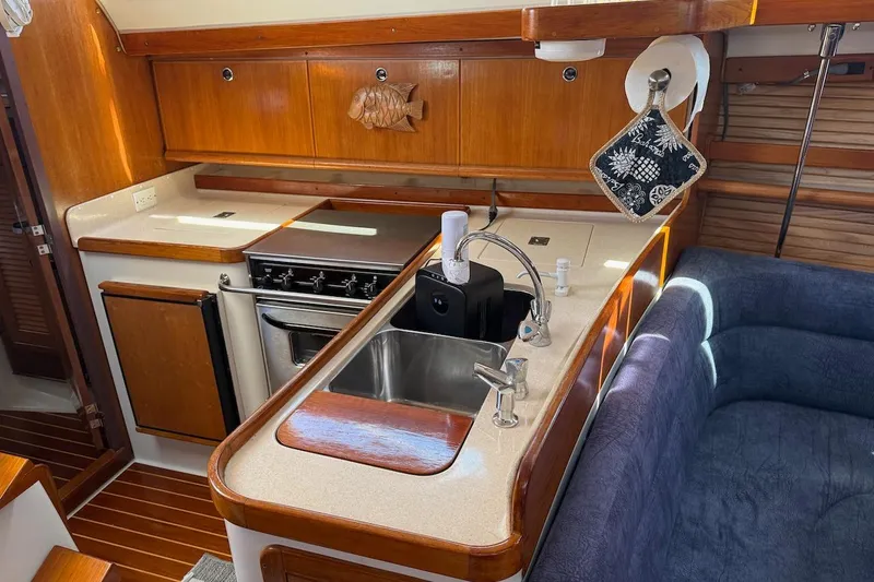 Slide: The Image of Cozy kitchen area in a 1998 Catalina 380 sailboat with wooden cabinetry and modern amenities. - 31