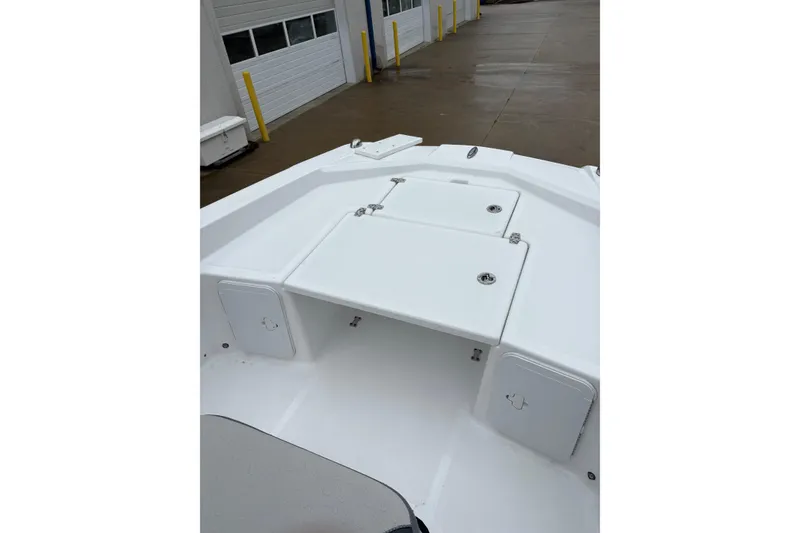 Slide: The Image of 2024 Scarab 235 ID boat deck with storage compartments, docked near a building. - 17