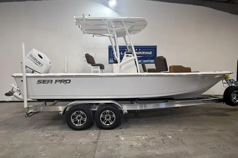 The Image of 2026 Sea Pro 230 Bay boat on trailer in showroom, featuring Suzuki outboard motor. - 0