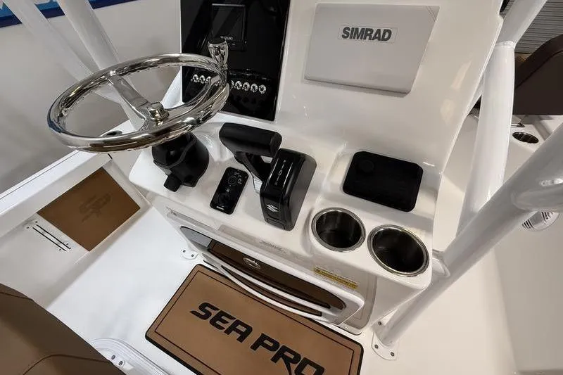 Slide: The Image of 2026 Sea Pro 230 Bay boat console with steering wheel, Simrad display, and cup holders. - 13