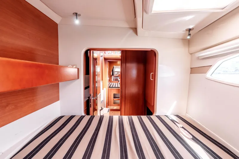 Slide: The Image of Cabin interior of 2011 Leopard 39 yacht with striped bedding and wooden accents. - 23