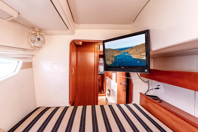 Slide: The Image of Interior of 2011 Leopard 39 yacht cabin with striped bedding and wall-mounted TV. - 25