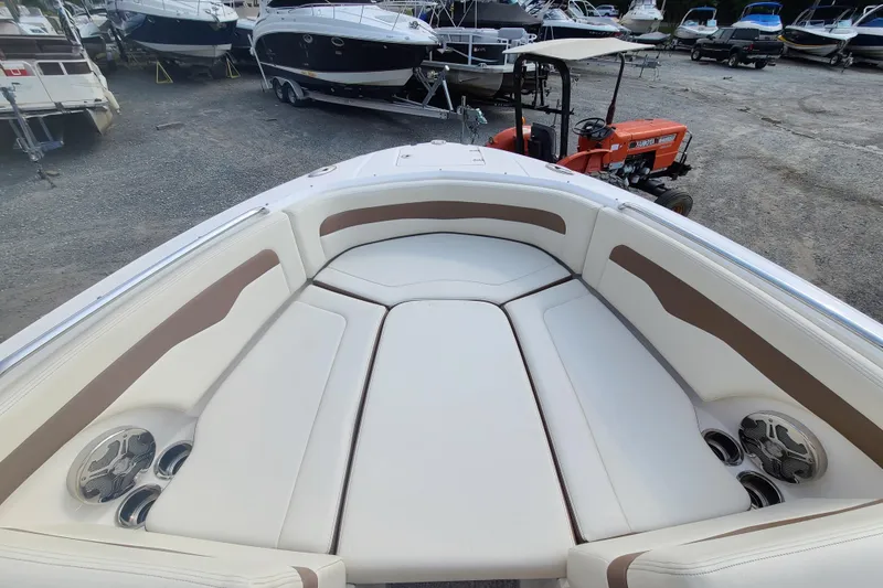 Slide: The Image of 2014 Chaparral 246 SSi boat interior with white and tan seating, parked in a marina. - 11
