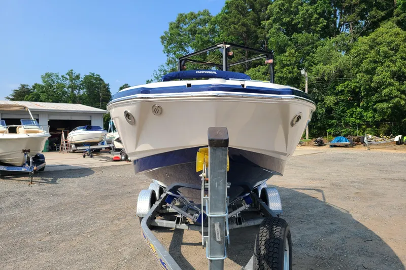 Slide: The Image of 2014 Chaparral 246 SSi boat on trailer, parked outdoors near trees and other boats. - 2