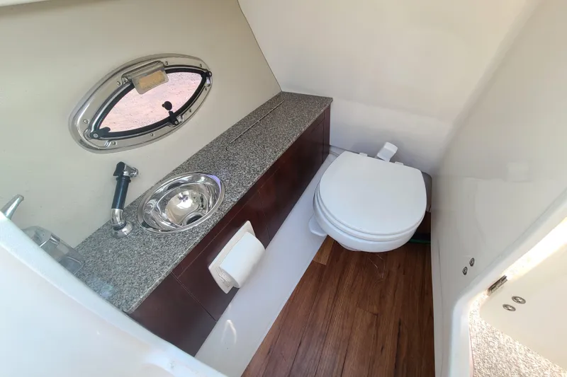 Slide: The Image of 2014 Chaparral 246 SSi boat bathroom with sink, toilet, and porthole window. - 38