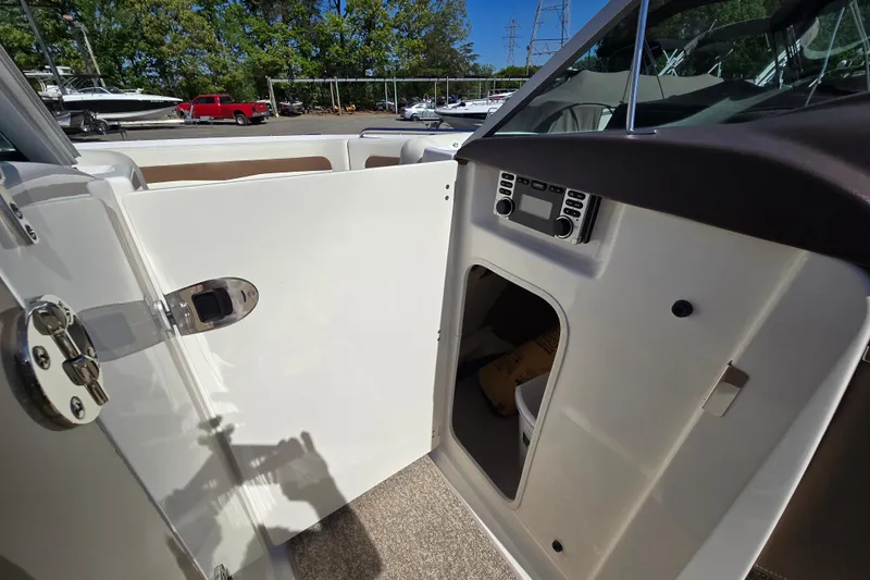 Slide: The Image of 2014 Chaparral 246 SSi boat interior with open storage compartment and control panel. - 54