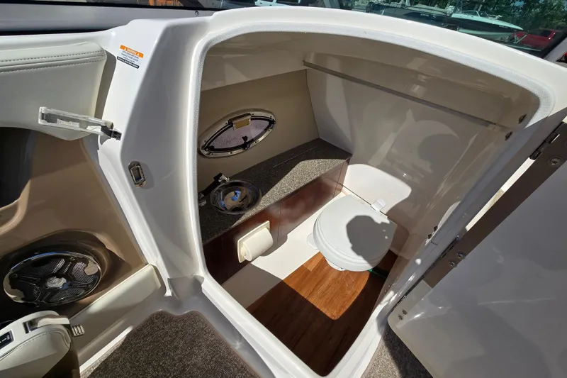 Slide: The Image of 2014 Chaparral 246 SSi boat interior with compact marine toilet and storage space. - 55