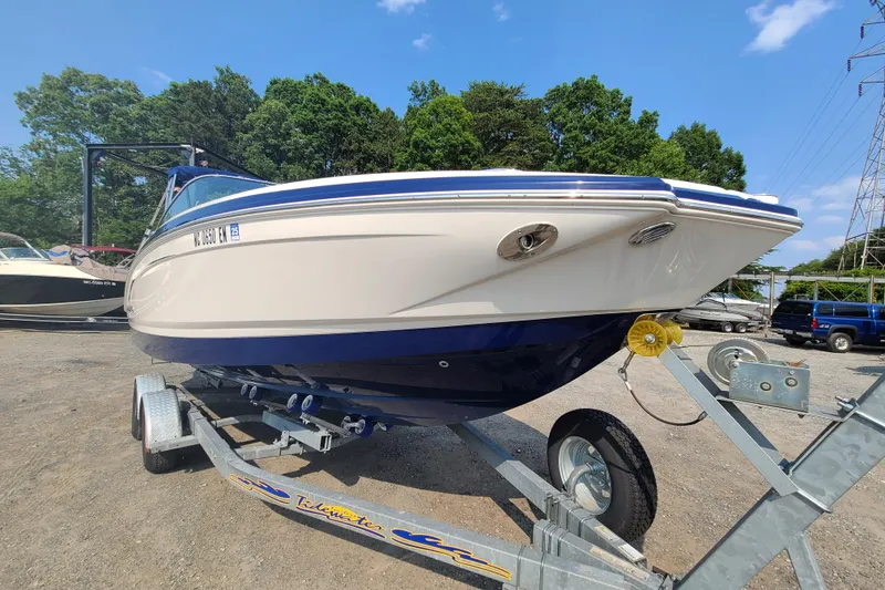 Slide: The Image of 2014 Chaparral 246 SSi boat on trailer, parked outdoors with trees in background. - 6
