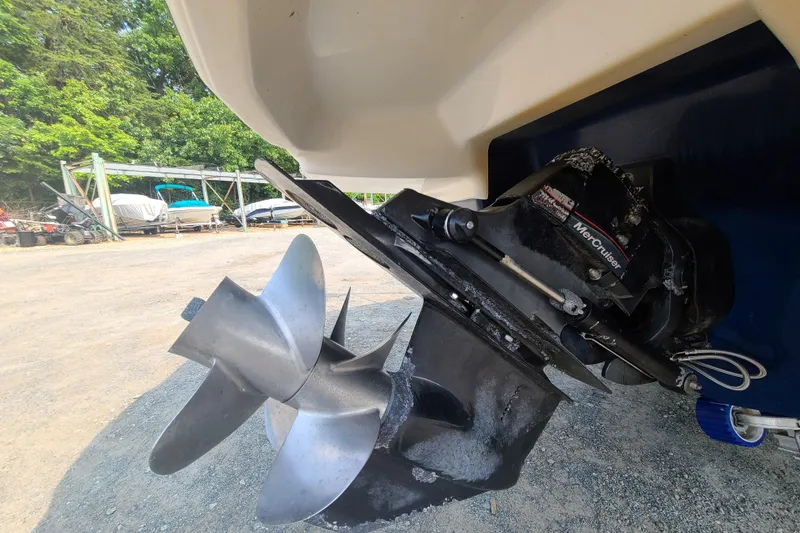 Slide: The Image of 2014 Chaparral 246 SSi boat with MerCruiser outdrive and propeller, parked on gravel. - 8