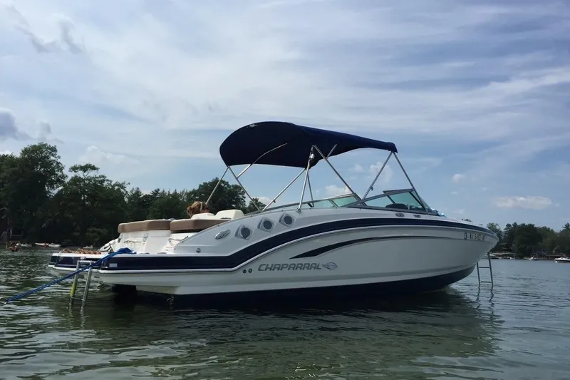 Slide: The Image of 2014 Chaparral 246 SSi boat with canopy on calm water, surrounded by trees. - 9