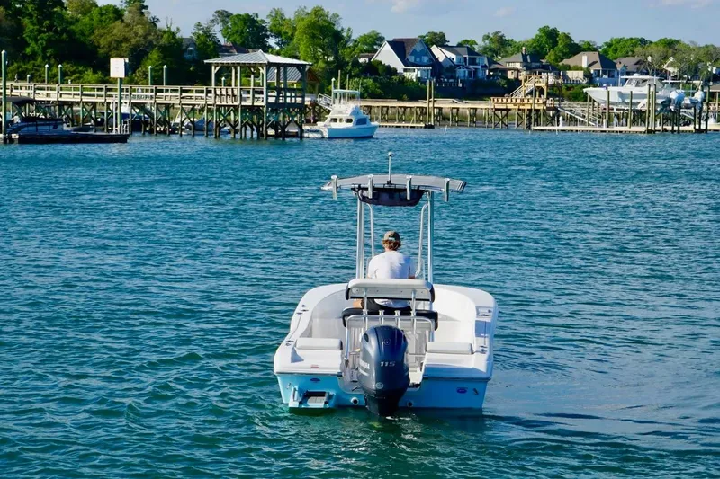 Slide: The Image of 2024 Tidewater 180 CC Adventure boat cruising on a scenic waterfront with docks and houses. - 11