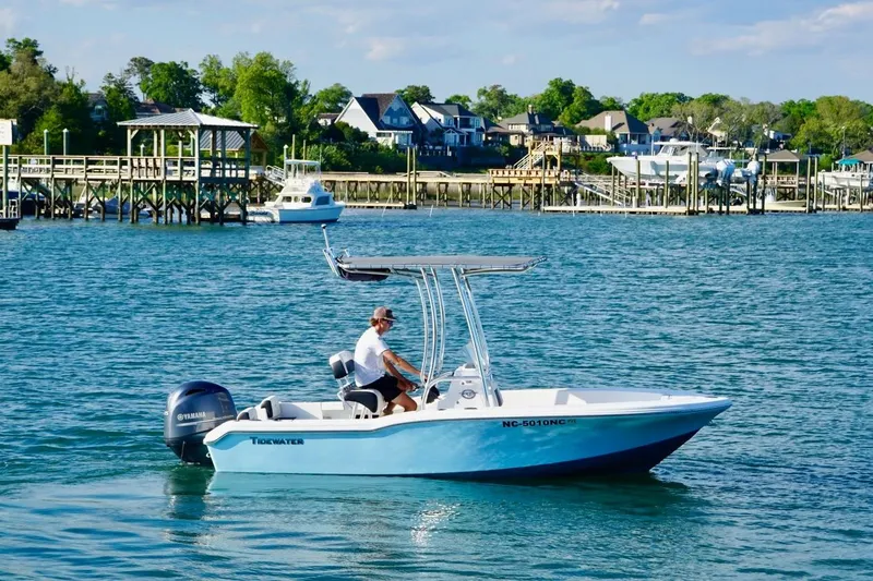 Slide: The Image of 2024 Tidewater 180 CC Adventure boat cruising on a scenic waterfront. - 2