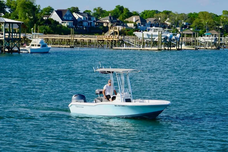 Slide: The Image of 2024 Tidewater 180 CC Adventure boat cruising near waterfront homes. - 8