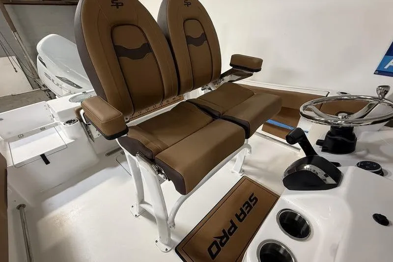 Slide: The Image of 2026 Sea Pro 242 Center Console boat interior with dual brown seats and steering wheel. - 13