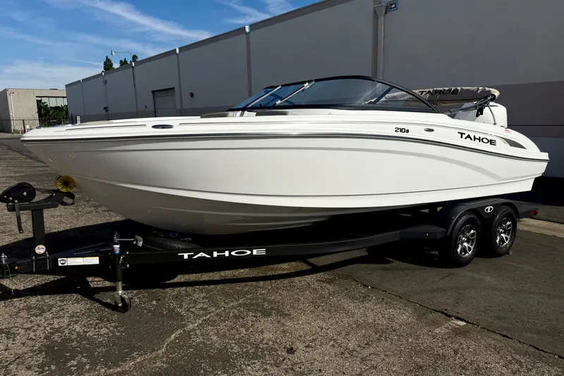 Slide: The Image of 2026 Tahoe 210 S boat on trailer, parked outdoors, side view. - 13
