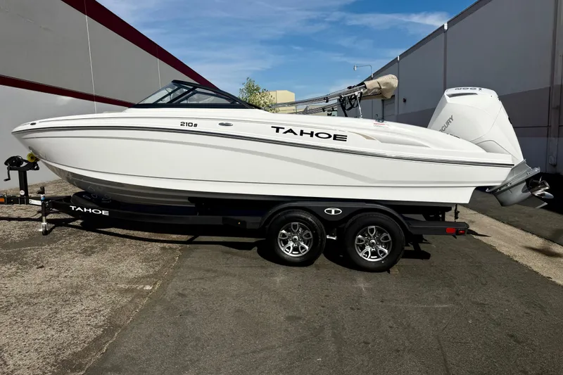Slide: The Image of 2026 Tahoe 210 S boat on trailer, parked outdoors, showcasing sleek white design. - 14