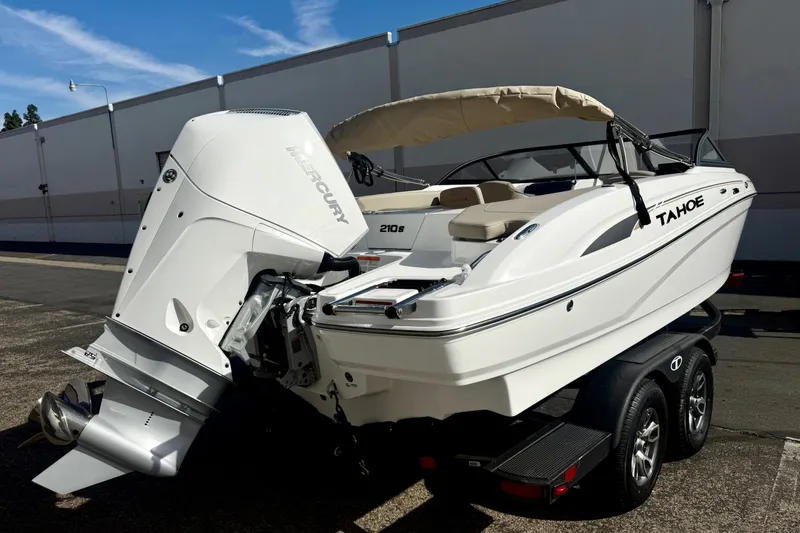 Slide: The Image of 2026 Tahoe 210 S boat with Mercury engine on a trailer, parked outdoors. - 18