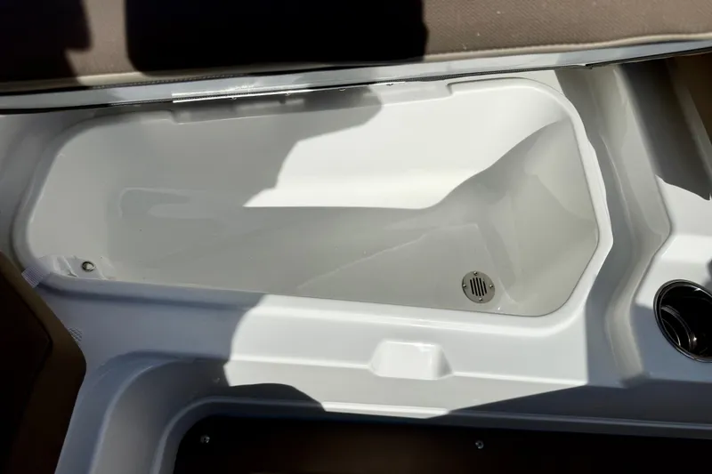 Slide: The Image of Storage compartment in 2026 Tahoe 210 S boat, featuring a drain and cup holder. - 23