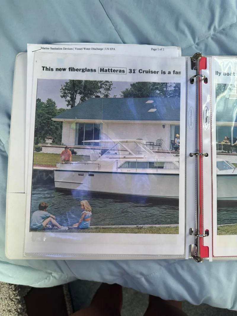 Slide: The Image of 1968 Hatteras 31 Flybridge boat docked by a waterfront house. - 25