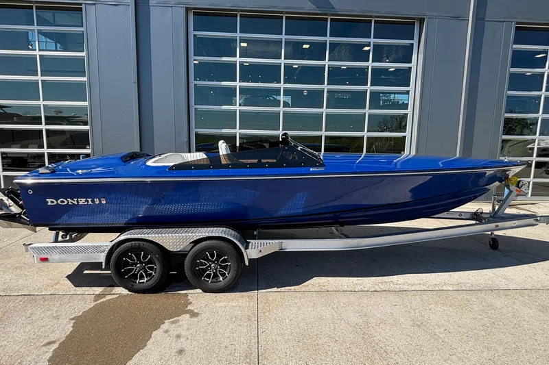 The Image of 2026 Donzi 22 Classic boat in blue on a trailer, parked outside a garage. - 0