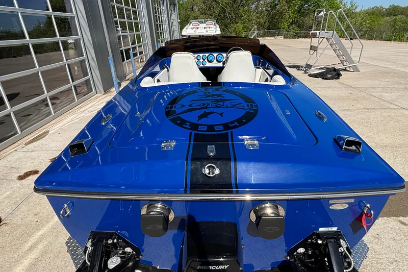 Slide: The Image of 2026 Donzi 22 Classic speedboat in vibrant blue, parked outdoors near a modern building. - 2