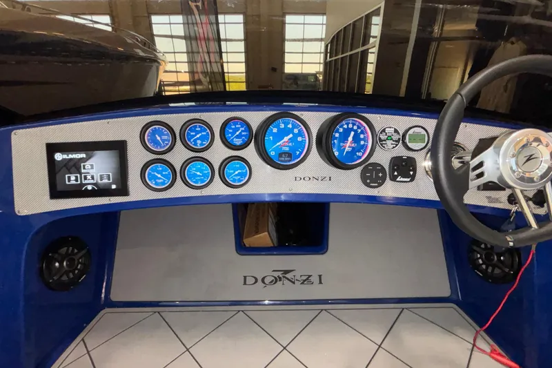 Slide: The Image of Dashboard of a 2026 Donzi 22 Classic boat with blue gauges and steering wheel. - 26