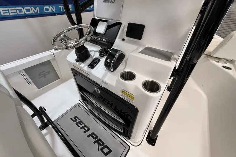 Slide: The Image of 2026 Sea Pro 250 Bay boat console with steering wheel, controls, and cup holders. - 14