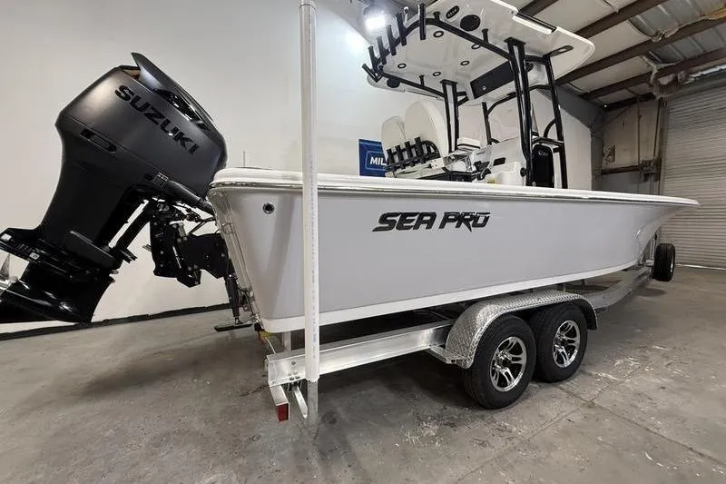 Slide: The Image of 2026 Sea Pro 250 Bay boat on trailer with Suzuki outboard motor in a garage. - 2