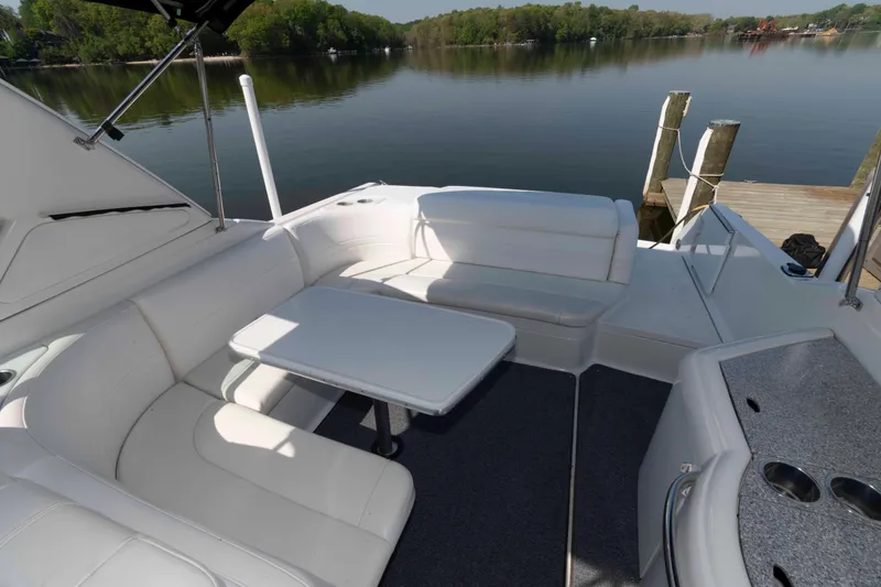 Slide: The Image of 2004 Formula 330 Sun Sport boat interior with white seating and table by a serene lake. - 14
