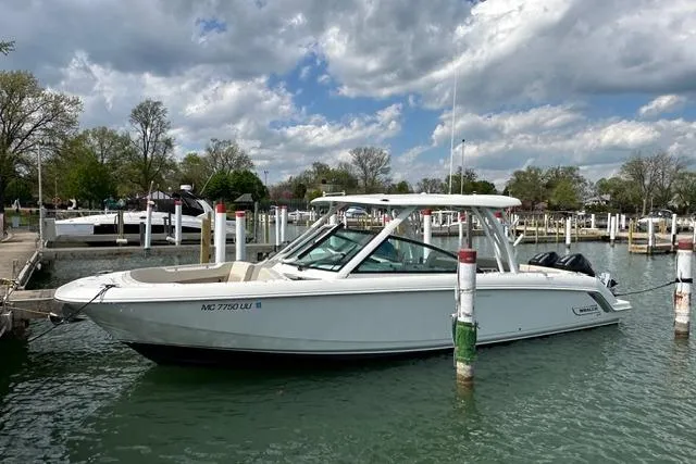 Slide: The Image of 2022 Boston Whaler 320 Vantage boat docked in a marina under cloudy skies. - 2