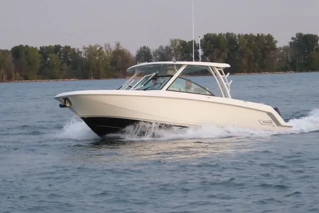 Slide: The Image of 2022 Boston Whaler 320 Vantage cruising on a lake with trees in the background. - 7