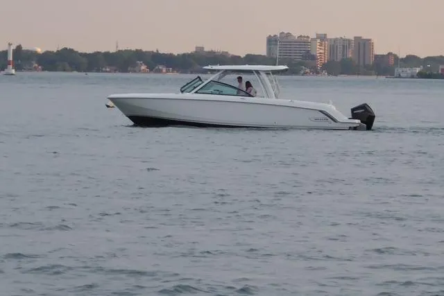 Slide: The Image of 2022 Boston Whaler 320 Vantage cruising on calm waters near urban skyline. - 9
