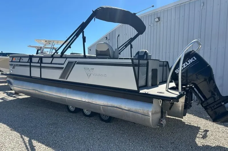 Slide: The Image of 2023 Viaggio Lago X-R 22 pontoon boat with Suzuki outboard motor, parked on gravel. - 3
