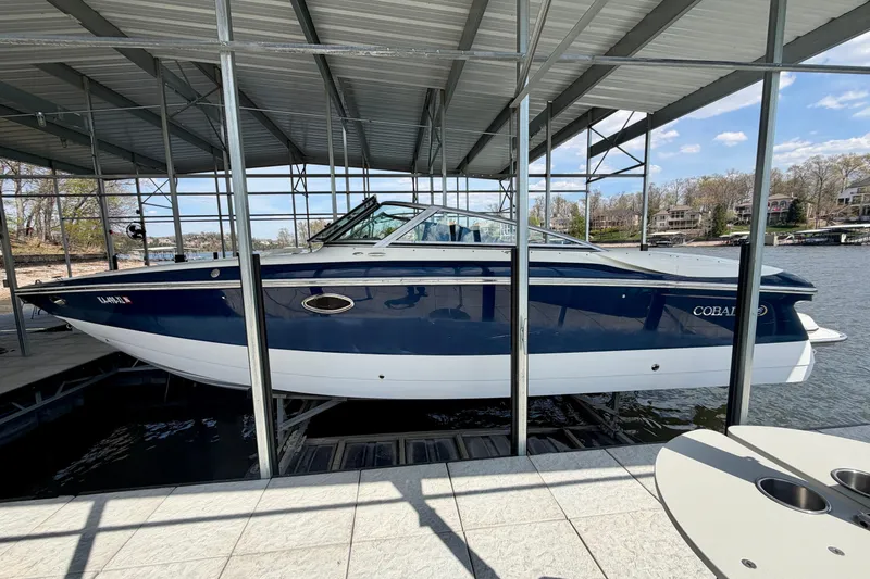 The Image of 2003 Cobalt 282 boat docked under a metal canopy on a sunny day. - 0