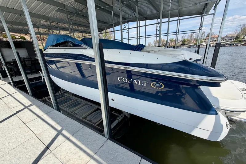 Slide: The Image of 2003 Cobalt 282 boat docked under a covered marina on a sunny day. - 2