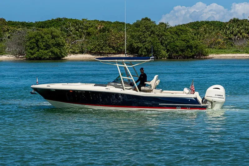 The Image of 2017 Chris-Craft Catalina 26 boat cruising on clear blue water near lush green shoreline. - 0