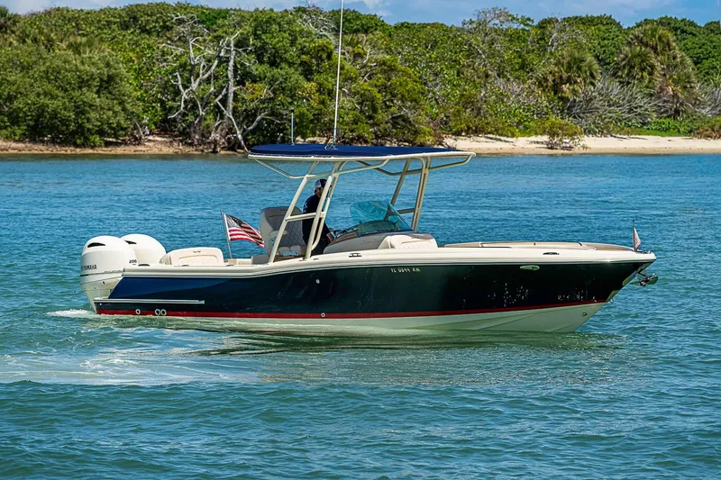 Slide: The Image of 2017 Chris-Craft Catalina 26 boat cruising on blue water near a lush shoreline. - 3