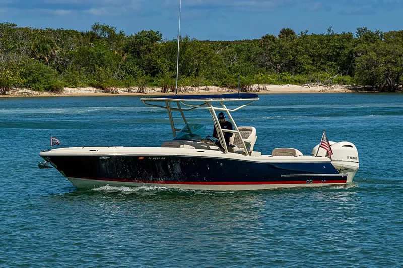 Slide: The Image of 2017 Chris-Craft Catalina 26 boat cruising on blue water near a lush shoreline. - 4