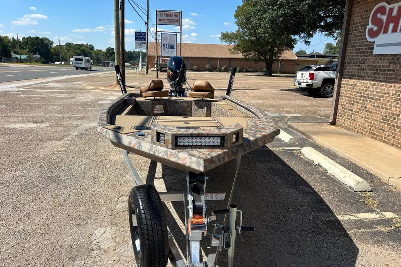 Slide: The Image of 2026 Xpress X18DB boat on trailer, parked near a brick building and road signs. - 4