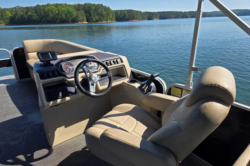 Slide: The Image of 2023 Godfrey Sweetwater 2286 C pontoon boat interior with steering console on a serene lake. - 19