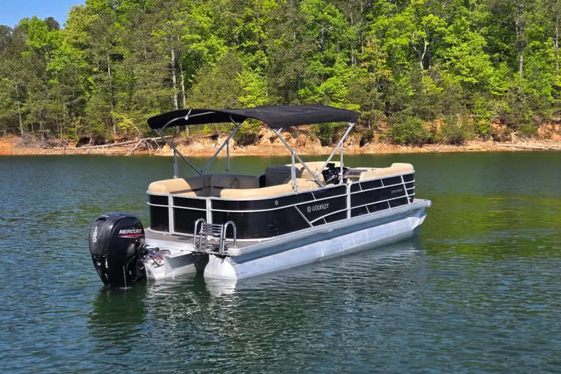 Slide: The Image of 2023 Godfrey Sweetwater 2286 C pontoon boat on a serene lake with lush forest backdrop. - 5
