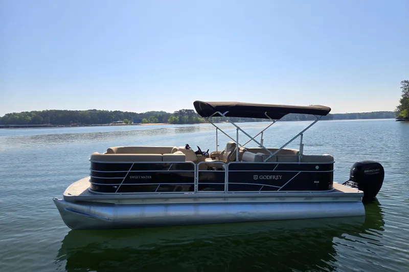Slide: The Image of 2023 Godfrey Sweetwater 2286 C pontoon boat on a serene lake. - 8