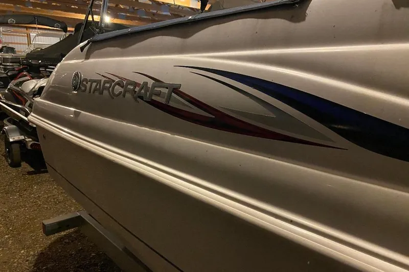 Slide: The Image of 2006 Starcraft 2000 IO Limited boat with sleek design and logo, parked indoors. - 4